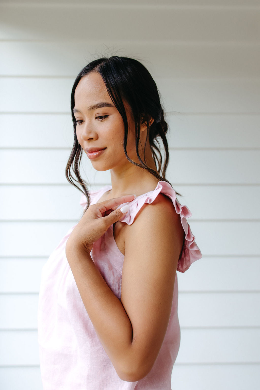 Woman wearing a pink linen top with ruffled sleeves against a white background